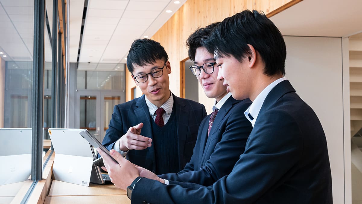 タブレットやスマートフォンを手にして話し合う社員